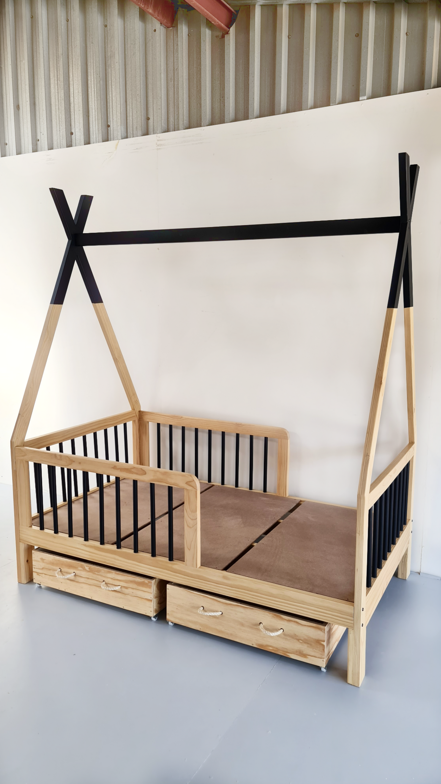 A Bamboo Teepee Bed with natural wood color and black rod rail supports. The bed is shown with storage drawers and a mattress, set against a plain background.