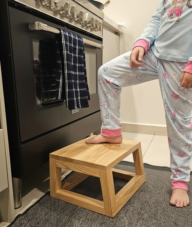 Child using wooden stool by oven