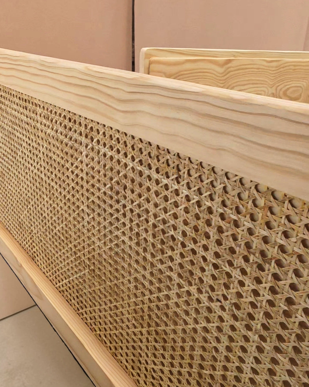 Close-up of a light natural wood frame with a woven cane or rattan panel, showing the texture and pattern of the woven material.