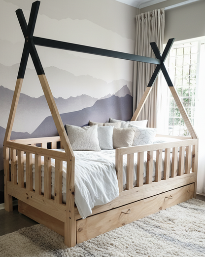 Wooden children's bed with a teepee-style canopy in a room with mountain wallpaper.