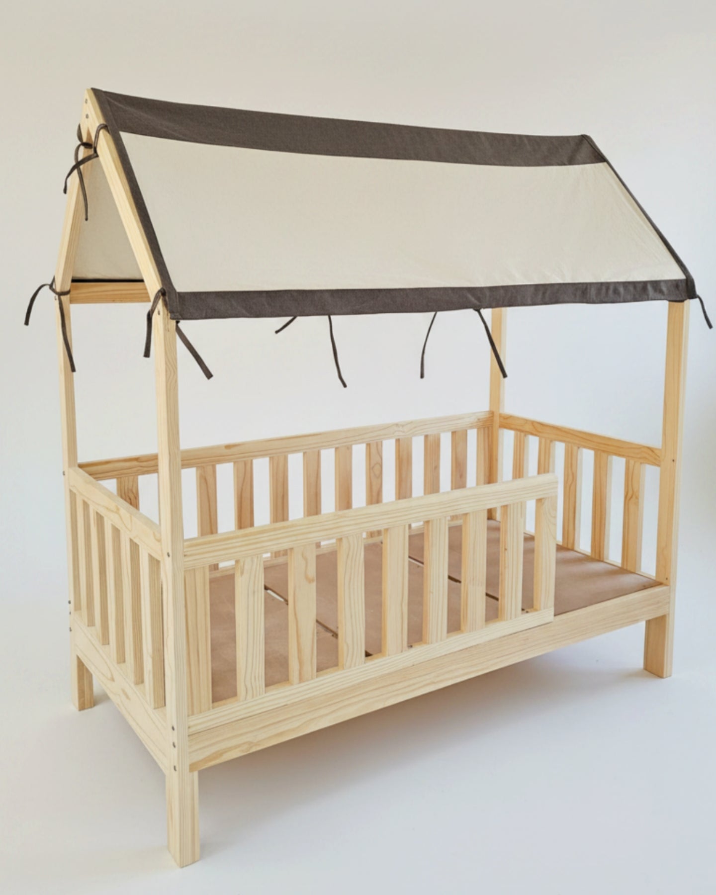 Wooden crib with a beige roof and brown trim on a white background